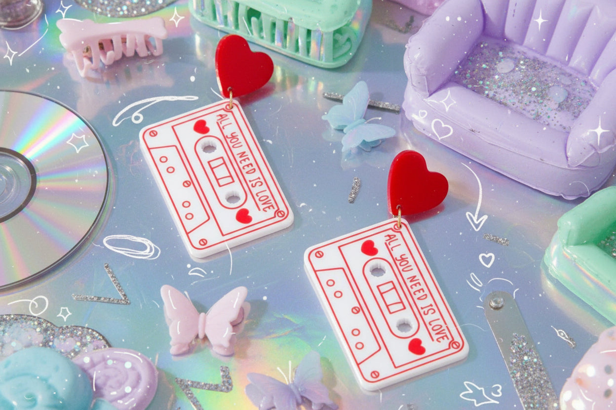 Cassette tape and heart-shaped earrings on a pink background
