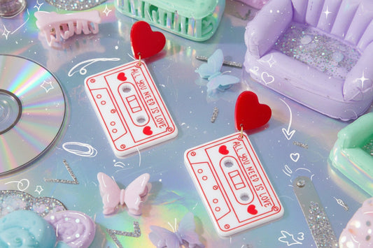 Cassette tape and heart-shaped earrings on a pink background